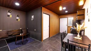 A room with a sofa, a dining table, and a kitchen area.