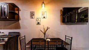 A dining area with a table, chairs, a vase, wall-mounted artwork, and a TV.