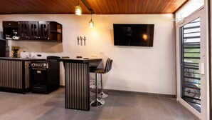 A modern kitchen with a built-in stove, a dining area with a bar counter, and a large TV mounted on the wall.
