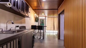 A modern kitchen with a bar area, a sink, and a dining table with chairs.