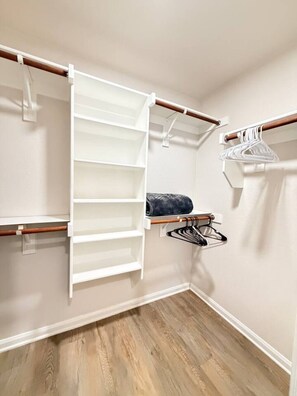 Ein begehbarer Kleiderschrank mit offene Regale, einer Kleiderstange und einem aufgerollten Handtuch.