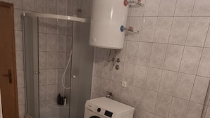 Un baño con ducha, lavadora, bañera y retrete.