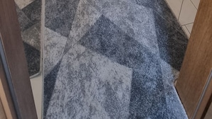 Un pasillo con alfombra estampada, puertas de madera y una lámpara en el techo.