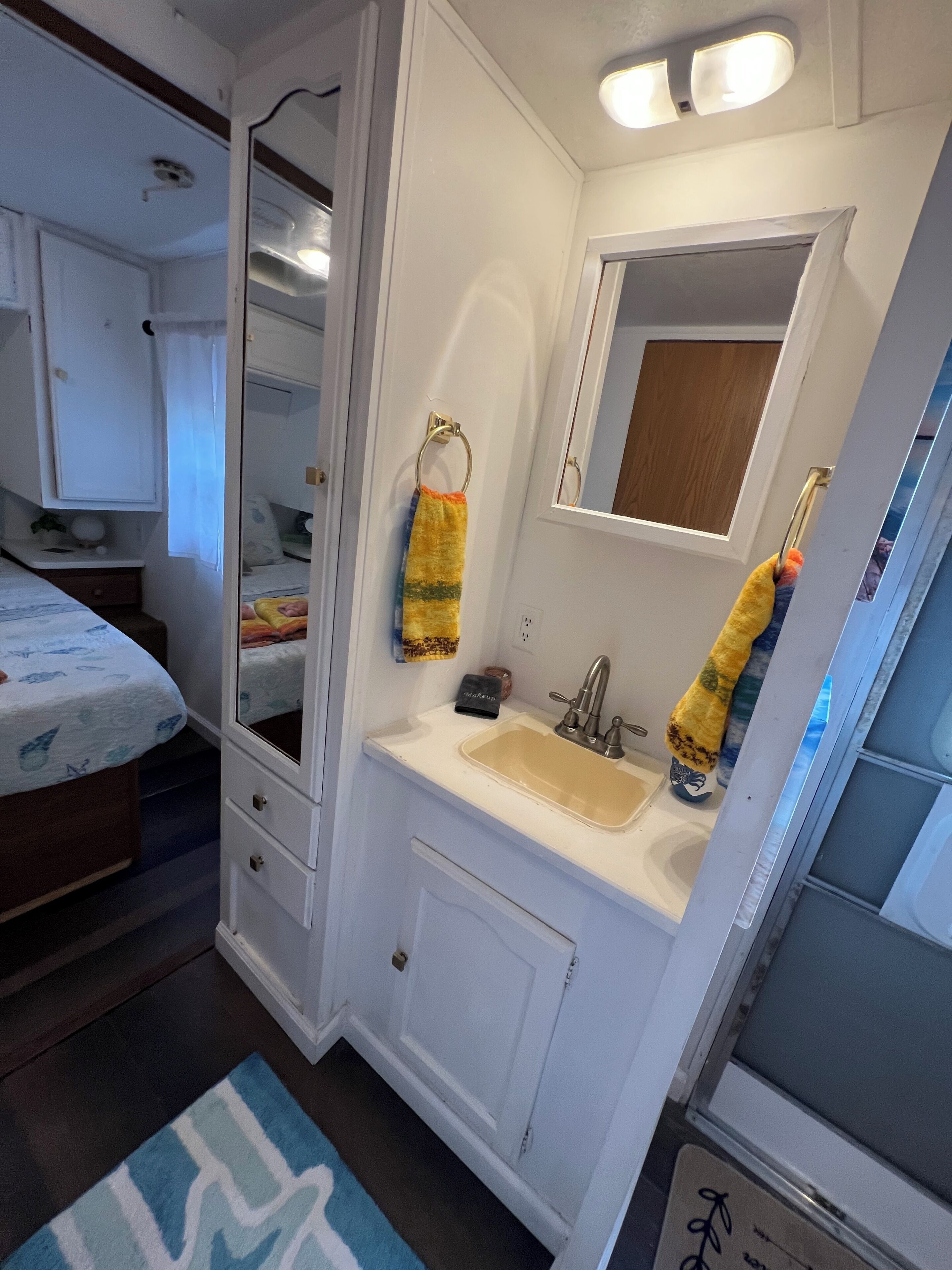 A compact bathroom with a sink, mirror, and towel rack.