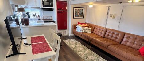 A compact living space with a kitchenette, a dining area, and a seating area with a sofa.