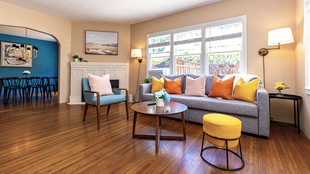 Uma sala de estar com sofá, poltronas, mesa de centro e um espaço de jantar com cadeiras e mesa.