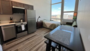 Una cocina compacta con electrodomésticos modernos, un comedor con mesa y sillas, y un amplio ventanal con vistas a la ciudad.