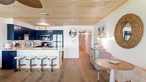 Una cucina moderna con pensili blu scuro, elettrodomestici in acciaio inossidabile e un'isola centrale con sgabelli.