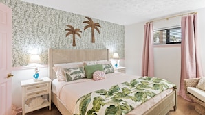 Una camera da letto con un letto, comodini, una finestra con tende e una parete decorata con un motivo a foglia.