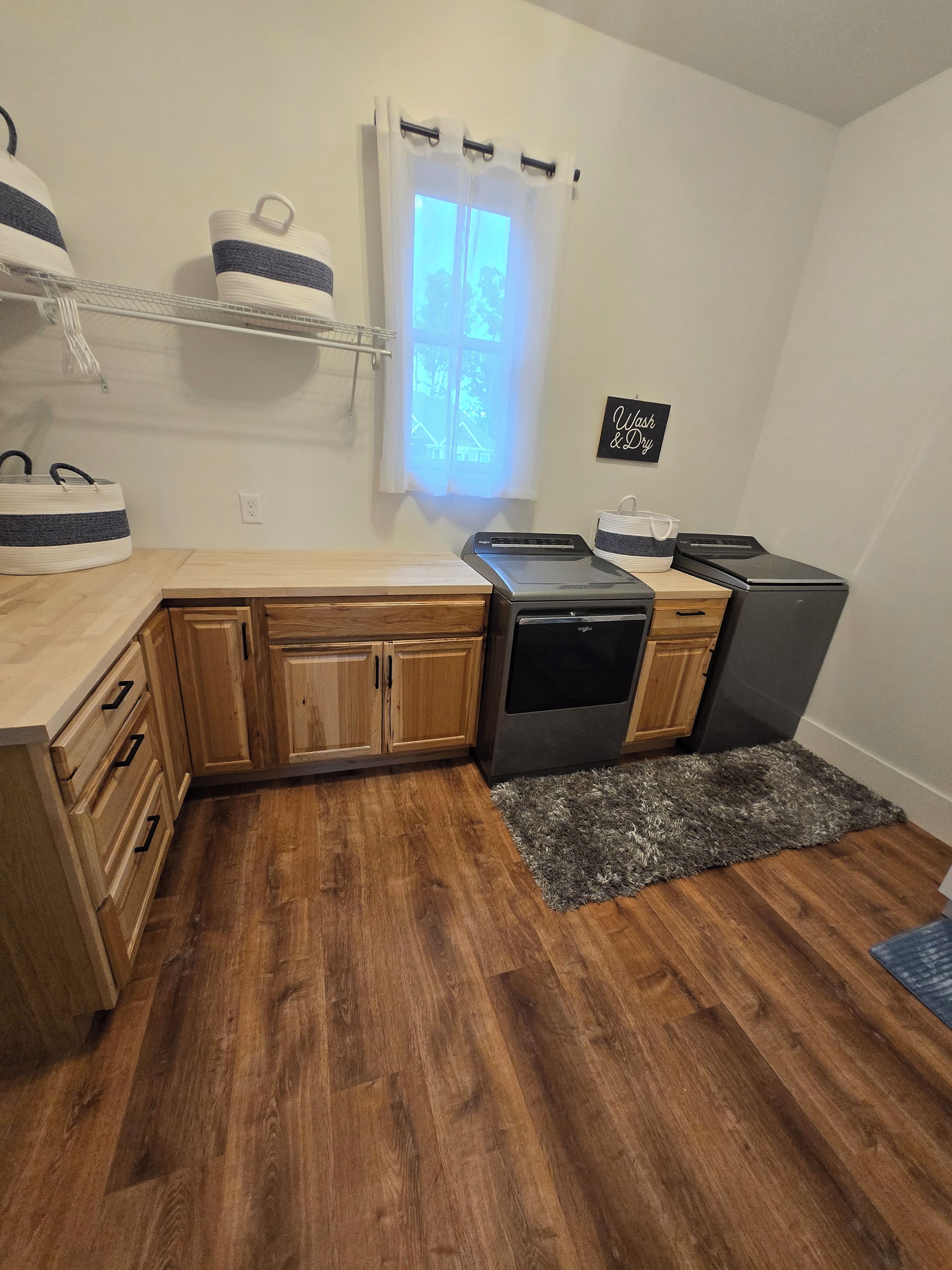 A compact kitchen with wooden cabinets, a built-in dishwasher, and a window with a view.