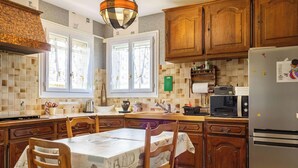 Une cuisine avec des meubles de rangement en bois, un réfrigérateur, un four à micro-ondes et une table à manger avec des chaises.