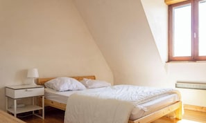 A bedroom with a bed, a nightstand, a lamp, and a window. - Cozy house for 9 people between beach and nature (FREHEL)