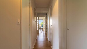 Ein Flur mit Holzboden, weißen Wänden und einer Tür zum Balkon.