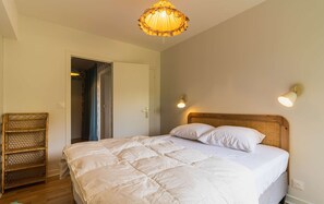 Un dormitorio con una cama, una puerta, una lámpara en la pared y una lámpara en el techo.