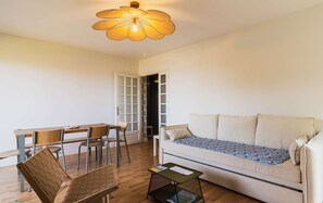 Una sala de estar acogedora con un sofá, una mesa de comedor con sillas y una lámpara de techo original.