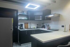 A modern kitchen with a central island, built-in microwave, and a coffee station.