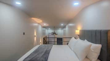 Un dormitorio moderno con una cama grande, cabecera gris e iluminación empotrada en el techo.