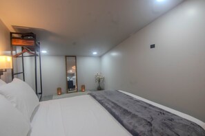 A hotel room with a bed, a bedside table with a lamp, a mirror, and a potted plant.