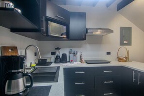 Una cocina moderna con armarios negros, una cafetera de acero inoxidable, un microondas y un horno empotrado.