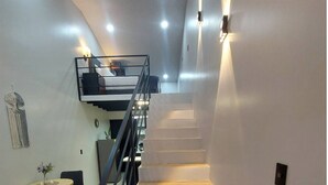 A modern interior with a staircase, a dining area with a round table and chairs, and a small seating area with a sofa. - Brand new Luxury Suites w/ jacuzzi. (El Castillo)