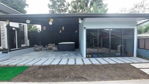 A covered outdoor area with a seating arrangement, a glass door entrance, and a pathway leading to a house. - Brand new Luxury Suites w/ jacuzzi. (El Castillo)