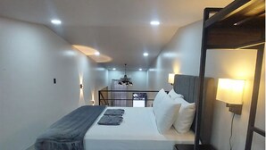 Una habitación de hotel moderna con cama, lámparas de noche y vistas a la ciudad.