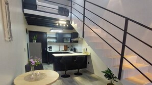 Una cocina moderna con comedor, escalera y planta en maceta.