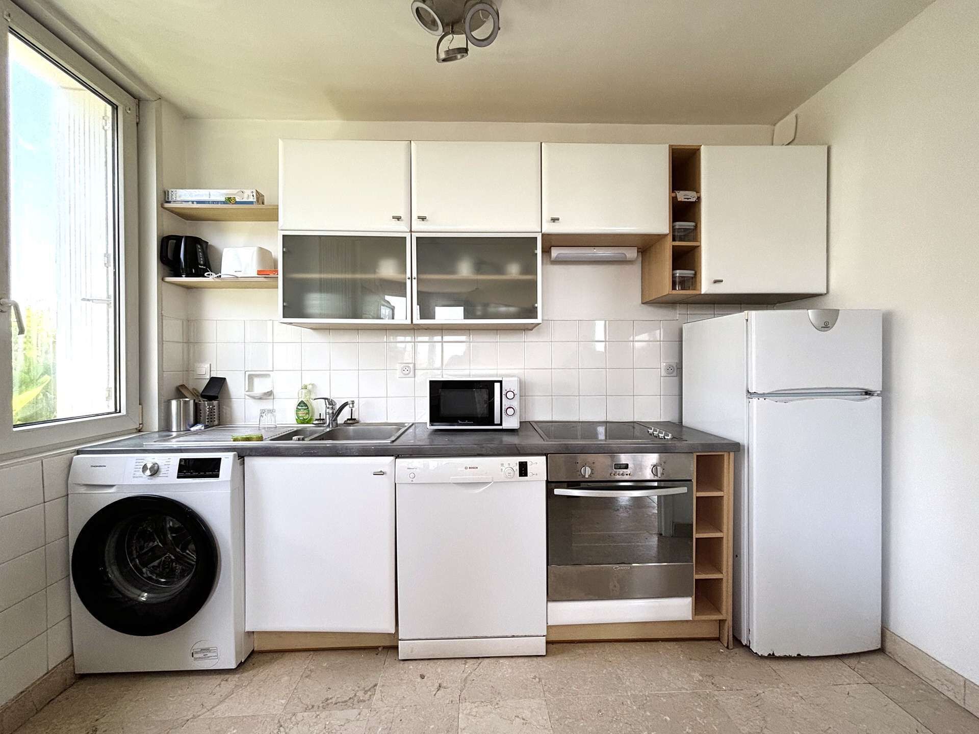A compact kitchen with a washing machine, dishwasher, microwave, oven, and refrigerator.