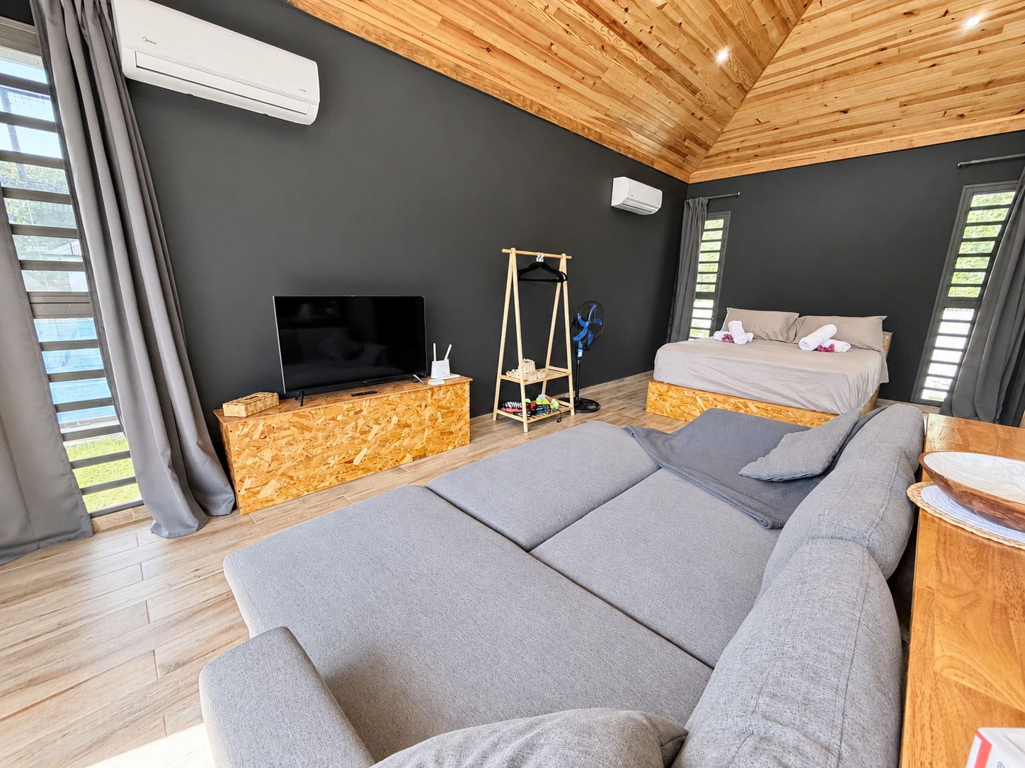 A modern bedroom with a large bed, a television, and a wooden floor.