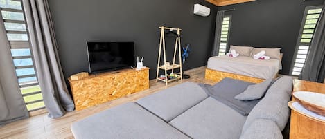 A modern bedroom with a large bed, a television, and a wooden floor.