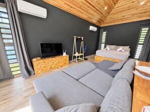 A modern bedroom with a large bed, a television, and a wooden floor. - Haumaru Bungalows  - 2 private pools and private PADEL court - 6 pers (Haapiti)
