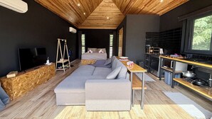 A modern interior with a wooden ceiling, a sofa, a television, a swing, and a kitchen area.