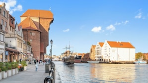 A riverside walkway with historic buildings, a tall brick tower, and a museum. - Jana Sobieskiego by Grand Apartments (Sopot)
