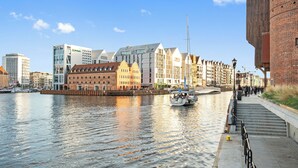 A waterfront cityscape with buildings, a canal, and a boat. - Jana Sobieskiego by Grand Apartments (Sopot)