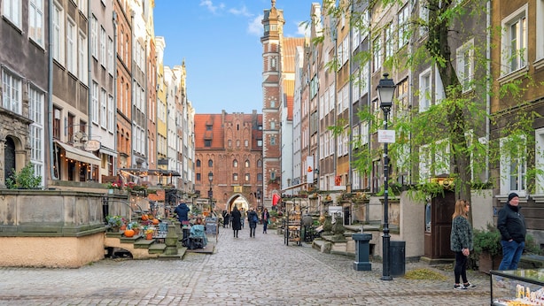 A cobblestone street lined with historic buildings, a prominent church tower, and outdoor market stalls. - Jana Sobieskiego by Grand Apartments (Sopot)