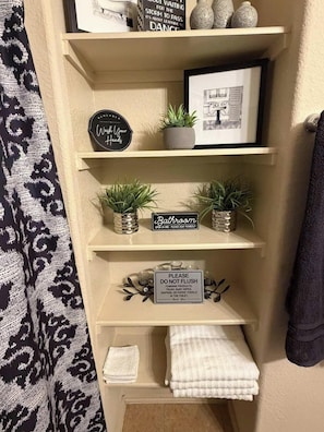 Un bagno con un cartello che indica l'apertura 24 ore su 24 e un cartello che vieta lo smaltimento di assorbenti, rifiuti, salviette umidificate, pannolini o asciugamani di carta.
