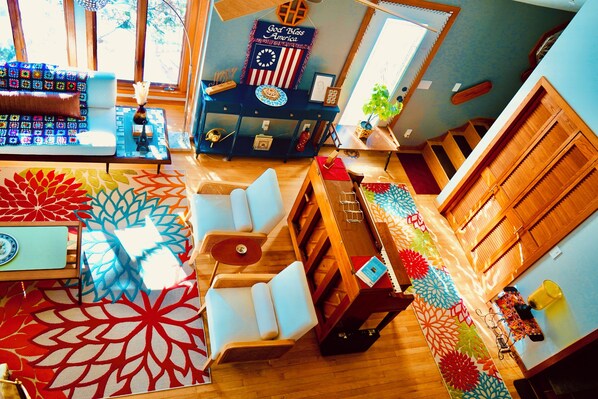 Une pièce comprenant un canapé, une table en bois, un tapis à motifs et un mur orné d’une horloge et d’un panneau.