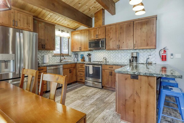A kitchen with wooden cabinets, stainless steel appliances, and a herringbone tile backsplash. - Northstar Cabin Escape (Truckee)