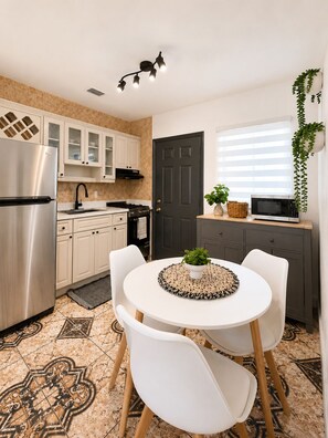 A modern kitchen with a refrigerator, stove, microwave, and a dining area with two chairs and a table. - Cozy 2BR Retreat w/Private Patio Near Downtown, Airport & Hospitals (Miami)
