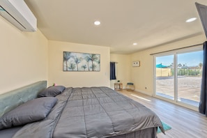 Ein Schlafzimmer mit einem Bett, einem Bild, einem Fenster und einer Klimaanlage.