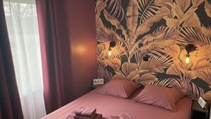A bed with a headboard featuring a leaf pattern, two bedside lamps, and a neatly made bed with folded towels. - Mobile Home Lodge (Bonzée)