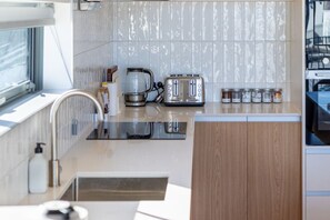 Une cuisine moderne avec un grille-pain en acier inoxydable, une bouilloire et une machine à café posés sur le plan de travail.