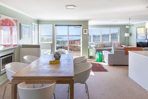 A modern living room with a dining area, large windows, and a view of the city.