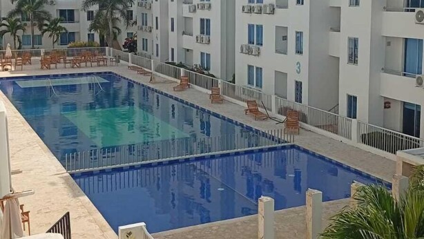 En flerplans boligbygning med swimmingpool og udendørs siddepladser.