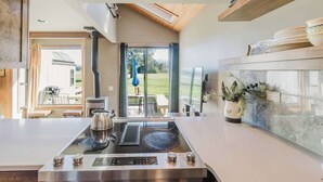 Een moderne keuken met een centraal eiland, een inbouwoven en uitzicht op het buiten.