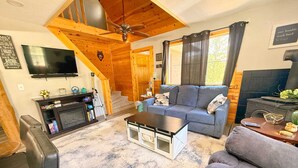 A cozy living room with a fireplace, a sofa, a coffee table, and a television. - The Buckhorn Lodge in Custer (Custer)