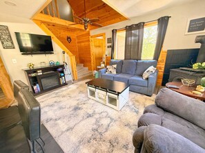 Una sala de estar acogedora con chimenea, un sofá, una mesita de centro y una televisión.