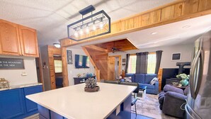 A modern kitchen with a central island, wooden accents, and a dining area with a sofa and table. - The Buckhorn Lodge in Custer (Custer)