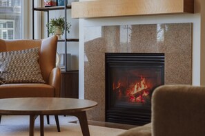 Ein Wohnzimmer mit Kamin, einer Couch, einem Couchtisch und einem Bücherregal mit Pflanze.