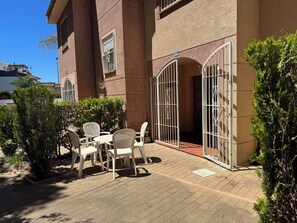 Ein Patio mit Tisch und Stühlen, ein verschlossener Eingang und ein Gebäude mit einer Hausnummer.
